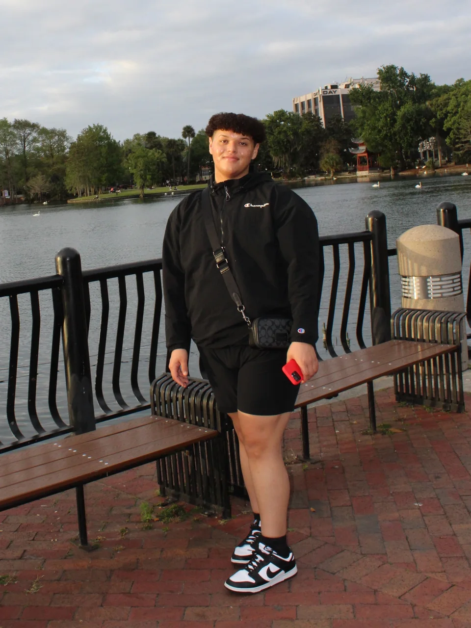 Jose in a black outfit beside the lake at golden hour.