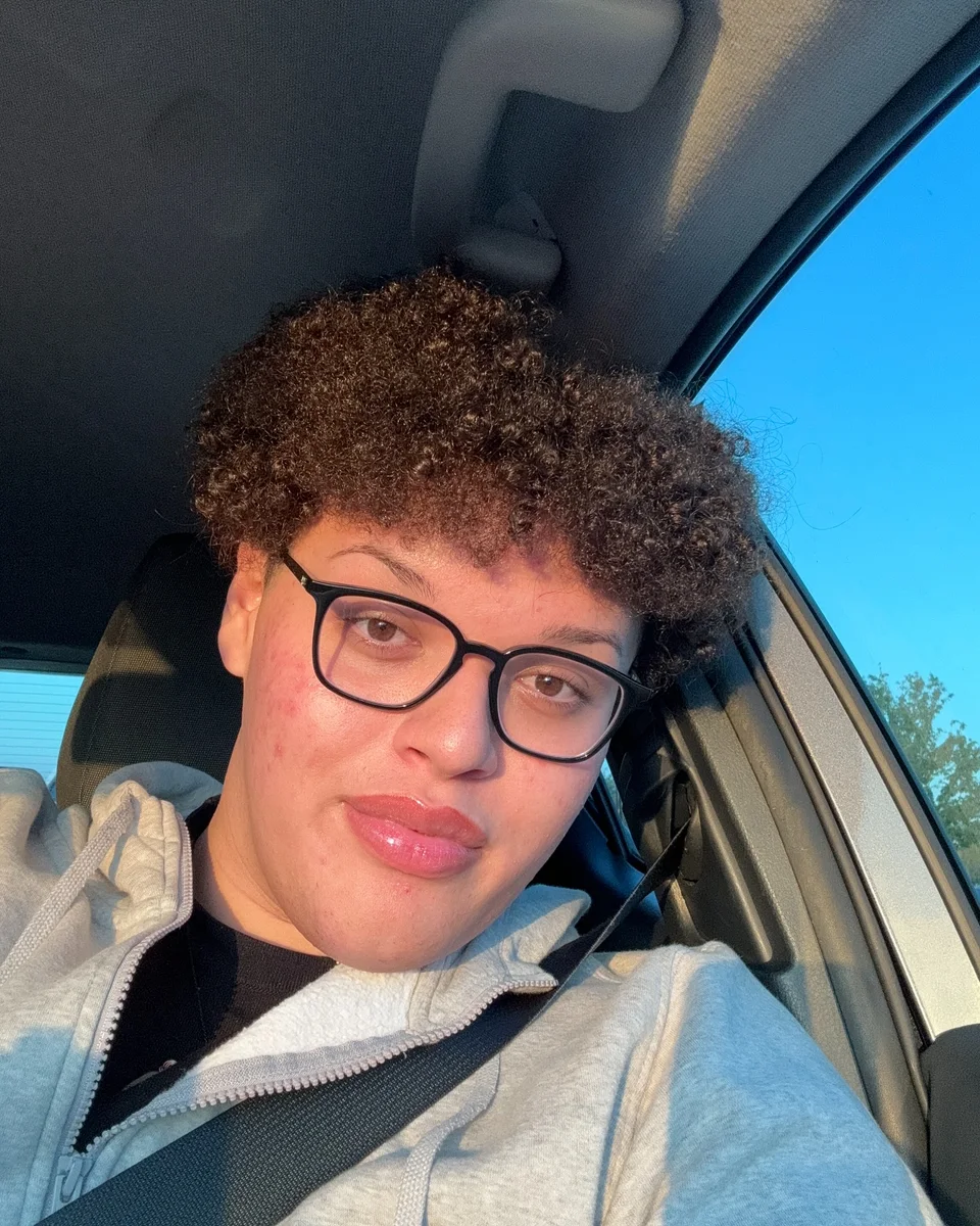 Jose wearing glasses in a sunlit car portrait.
